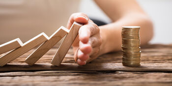 928087964 Close-up Of A Businesswoman's Hand Stopping The Wooden Blocks From Falling On Stacked Coins